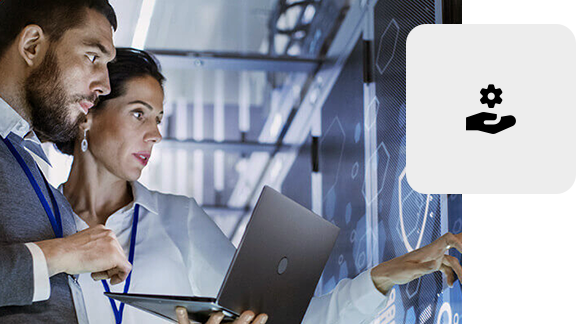 Zwei IT-Spezialisten stehen vor einem Serverschrank und arbeiten mit einem Laptop