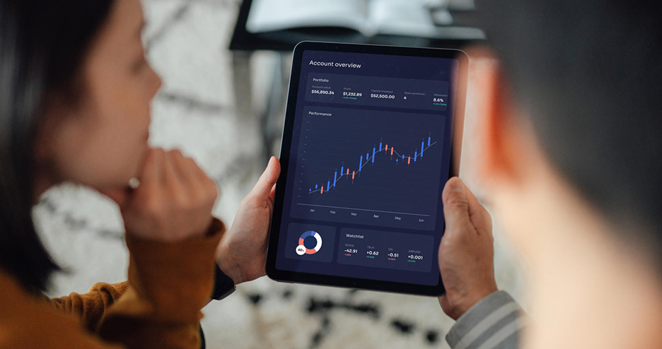 Eine Frau und ein Mann halten ein Tablet auf dem eine Auswertung zu sehen ist. 